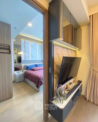 Modern bedroom with stylish decor and large TV unit, featuring elegant lighting and cozy ambiance.