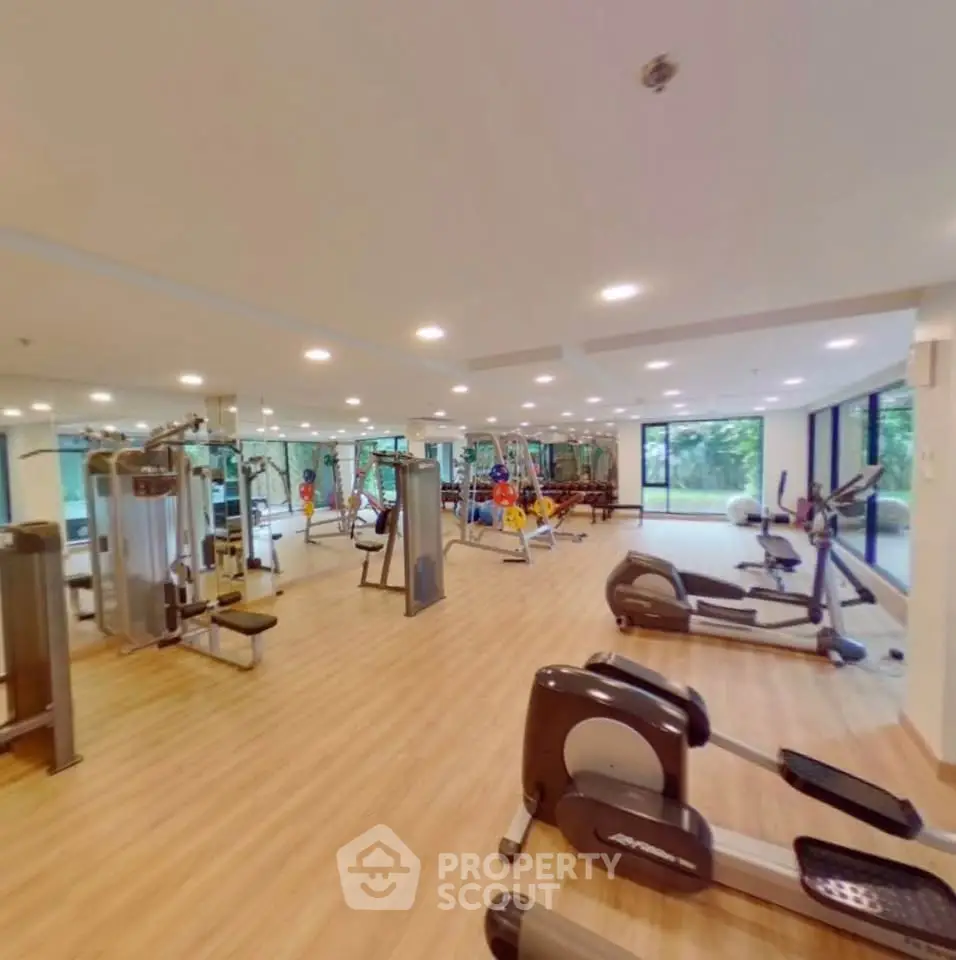Spacious modern gym with state-of-the-art equipment and large windows offering scenic views.