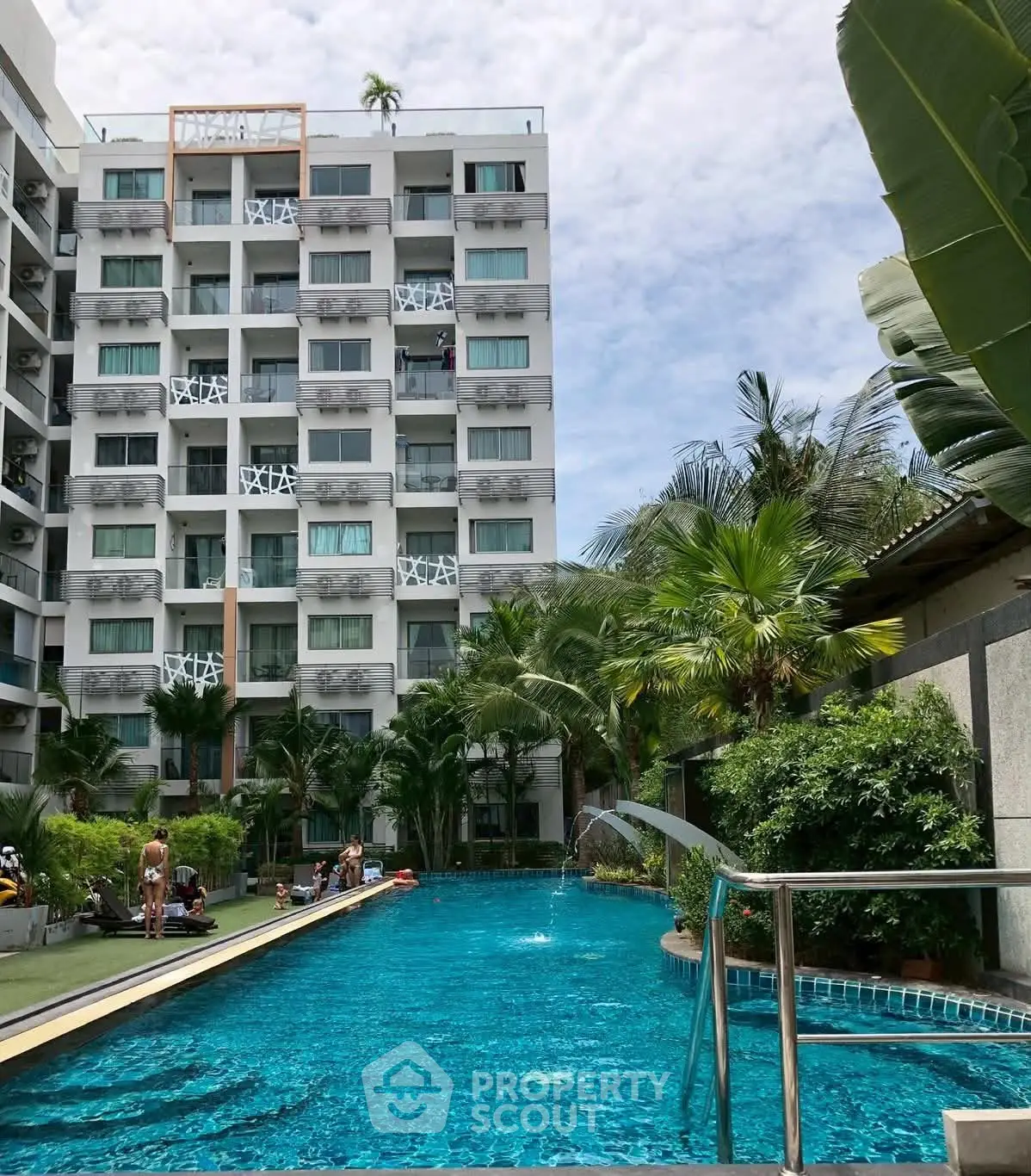 Luxurious apartment complex with a stunning outdoor pool and lush tropical landscaping.