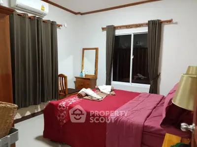 Cozy bedroom with red bedding, wooden furniture, and air conditioning for comfort.