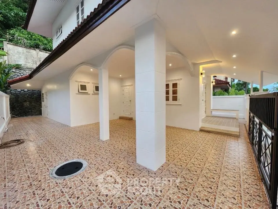 Spacious covered outdoor area with tiled flooring and elegant arches in a modern home.