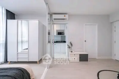 Modern minimalist bedroom with sleek wardrobe and compact kitchen area.