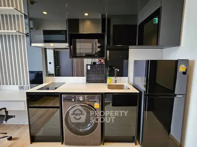 Modern kitchen with sleek black cabinets, built-in appliances, and compact design.