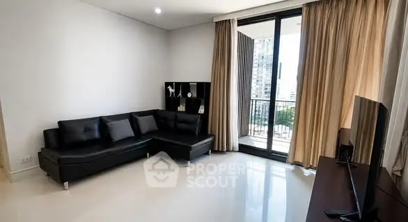 Modern living room with sleek black sofa and balcony view in luxury apartment.