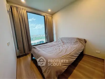 Cozy bedroom with large window offering stunning city view, perfect for relaxation and comfort.