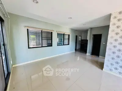 Spacious unfurnished living room with large windows and tiled flooring in modern home.