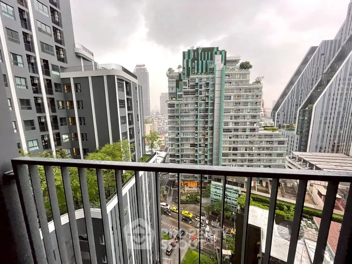 Stunning urban view from a high-rise balcony overlooking modern cityscape with lush greenery.