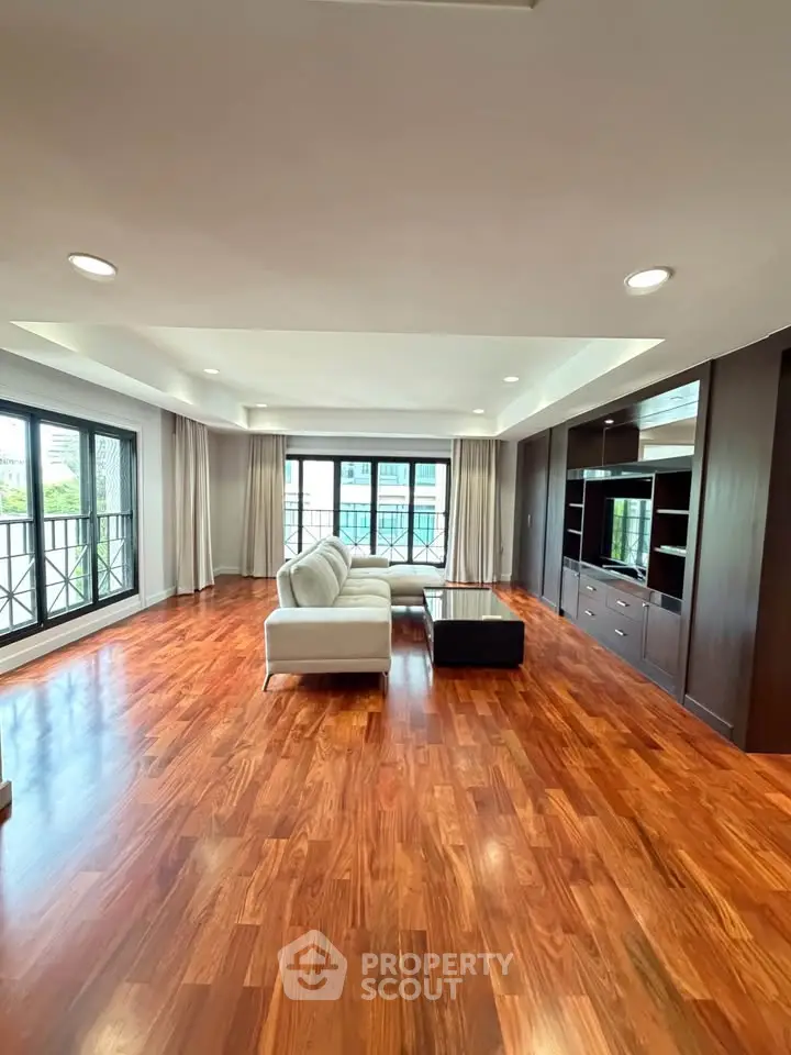 Spacious living room with hardwood floors and modern furniture in a luxury apartment.