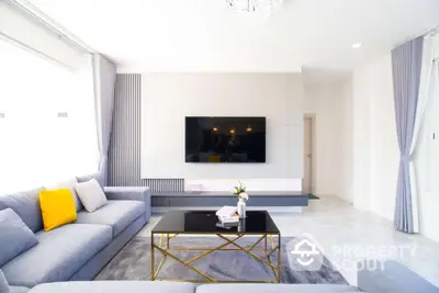 Modern living room with sleek design, large TV, and stylish furniture, perfect for relaxation and entertainment.