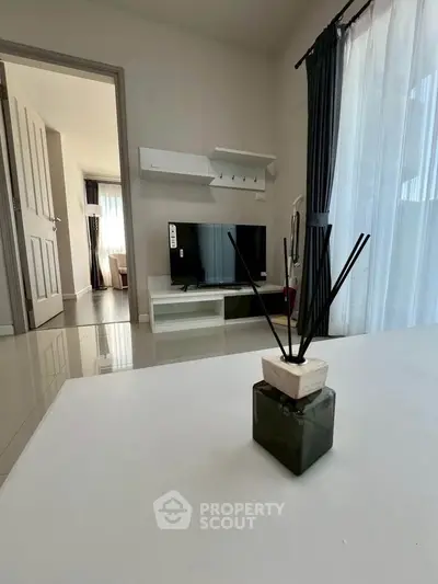 Modern living room with sleek TV stand and elegant decor, featuring natural light and stylish curtains.