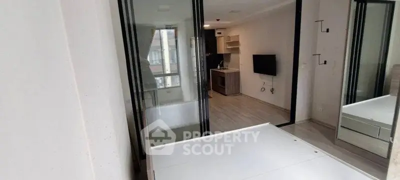 Modern apartment interior with glass partition, sleek kitchen, and wall-mounted TV, ideal for urban living.