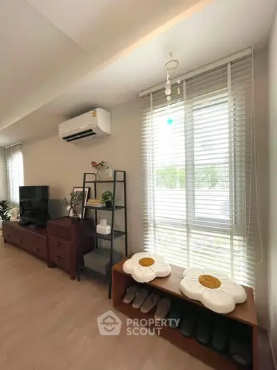 Modern living room with stylish decor, air conditioning, and ample natural light from large windows.