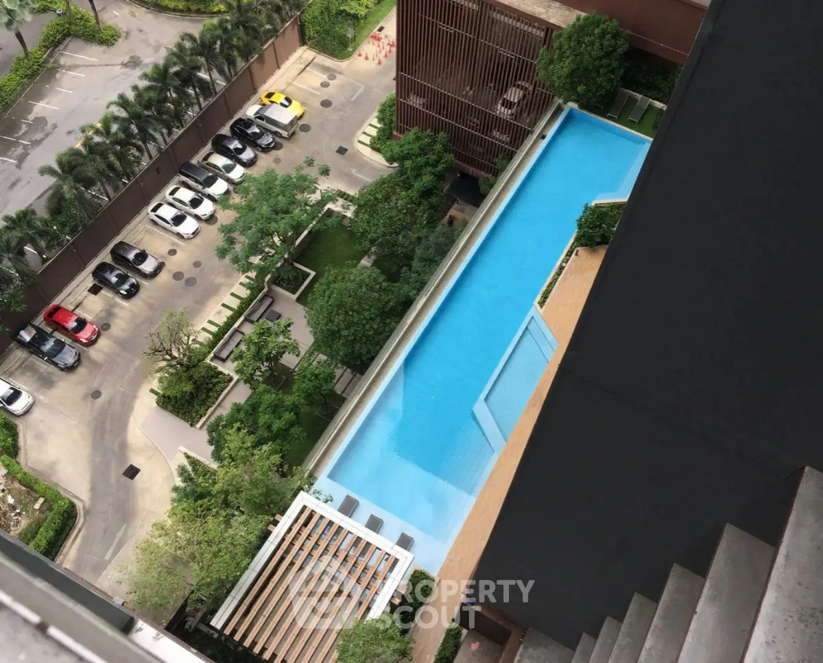 Stunning aerial view of luxury apartment pool and lush garden with ample parking space.