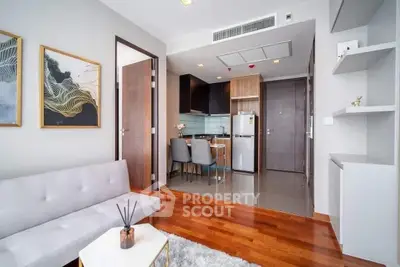 Modern living room with open kitchen, wooden flooring, and stylish decor in a contemporary apartment.