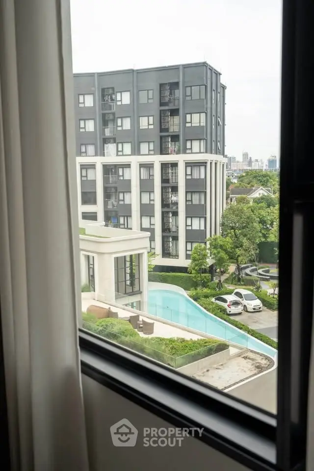 Modern apartment view with pool and lush greenery, offering urban living with serene surroundings.