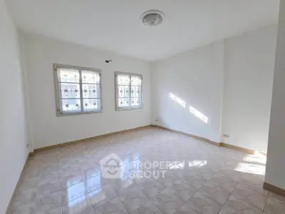 Spacious sunlit room with tiled flooring and decorative windows, perfect for versatile living space.