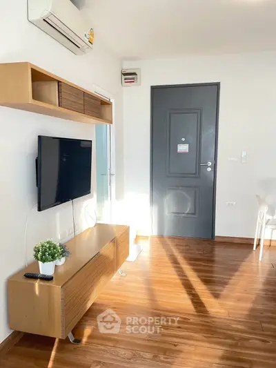 Modern living room with wooden flooring and wall-mounted TV, bright and inviting.