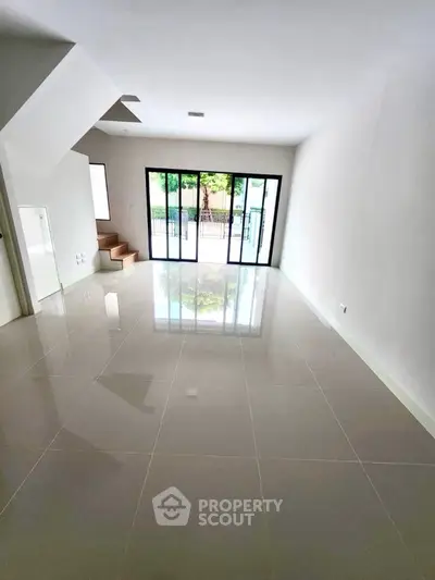 Spacious modern living room with large windows and glossy tiled floor