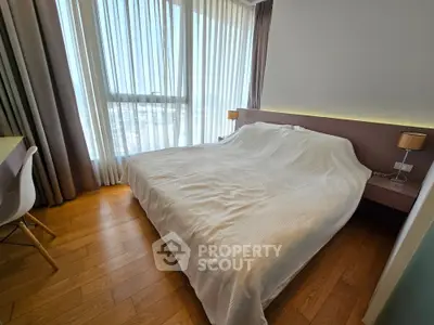 Modern bedroom with large window and elegant decor in a high-rise apartment.