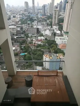 Stunning cityscape view from a high-rise balcony with modern wooden seating area.