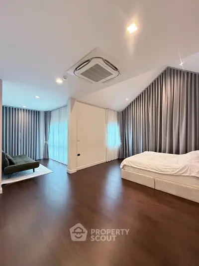 Spacious modern bedroom with elegant curtains and wooden flooring