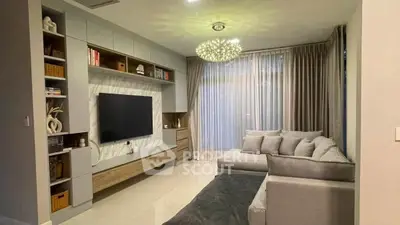 Modern living room with stylish decor and large TV, featuring cozy gray sofa and elegant lighting.