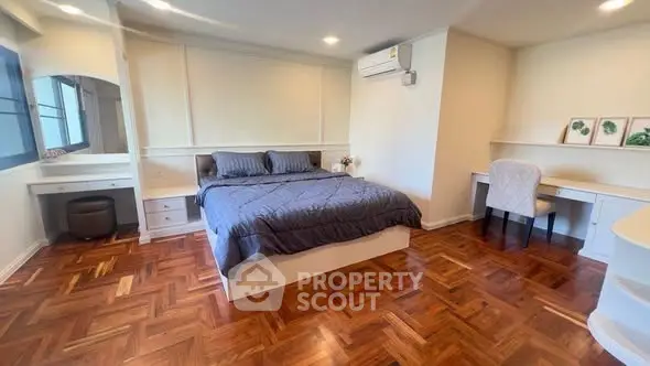 Spacious bedroom with elegant parquet flooring and modern furnishings