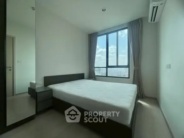 Spacious bedroom with large window offering stunning city views and ample natural light.