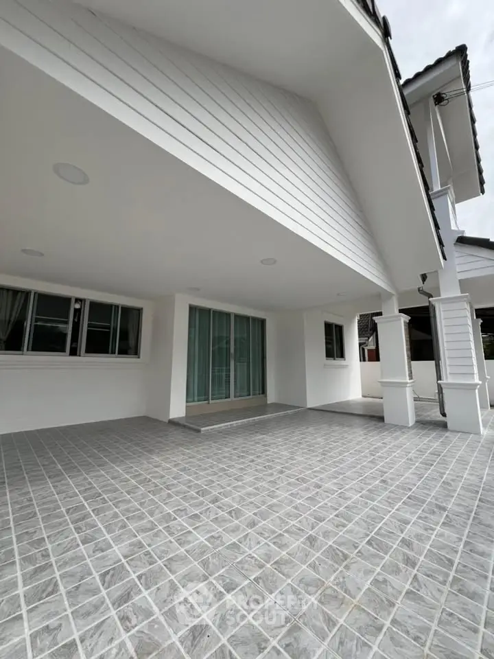 Spacious modern home exterior with tiled patio and large windows