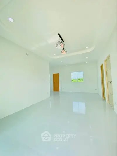 Spacious and bright empty room with modern lighting and large window view.