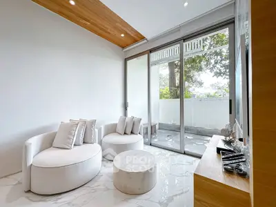 Modern living room with stylish furniture and large glass doors opening to a serene patio.
