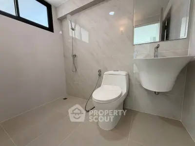 Modern bathroom with sleek fixtures and large tiles, featuring a shower and toilet in a minimalist design.