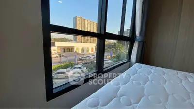 Spacious bedroom with large window offering city view and natural light
