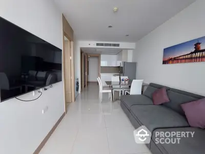 Spacious modern living room with glossy tiled floors, large comfortable sofa, and an open dining area leading to a well-lit hallway, perfect for urban living.