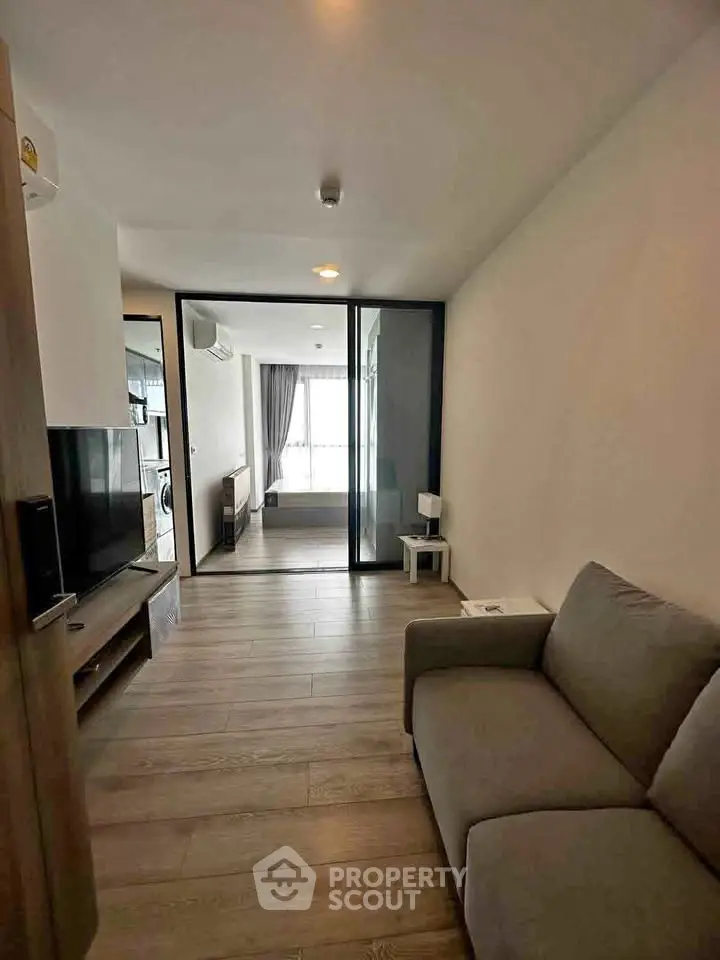 Modern living room with sleek design and glass partition, featuring cozy sofa and wooden flooring.