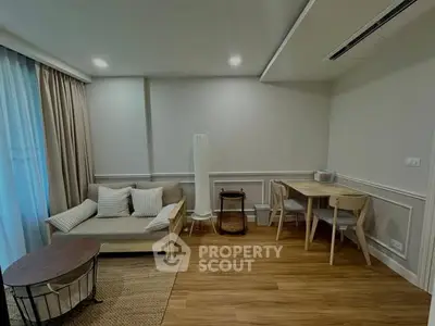 Cozy living room with modern decor and wooden flooring, featuring a comfortable sofa and dining area.
