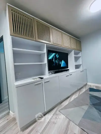Modern living room with sleek built-in storage and TV unit, featuring stylish wood accents and contemporary flooring.