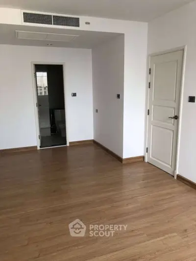 Spacious empty room with wooden flooring and white walls, ready for customization.