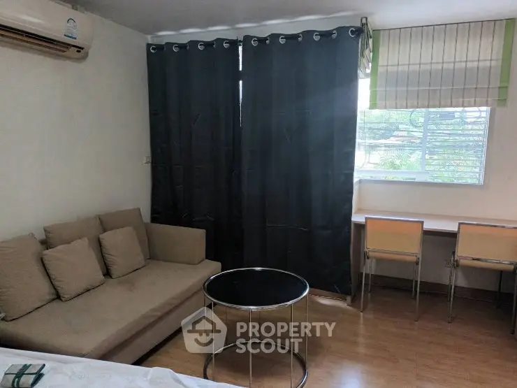 Cozy living room with modern sofa, round coffee table, and window view.