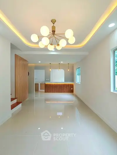 Modern living room with elegant lighting and open layout, featuring sleek tile flooring and large windows.
