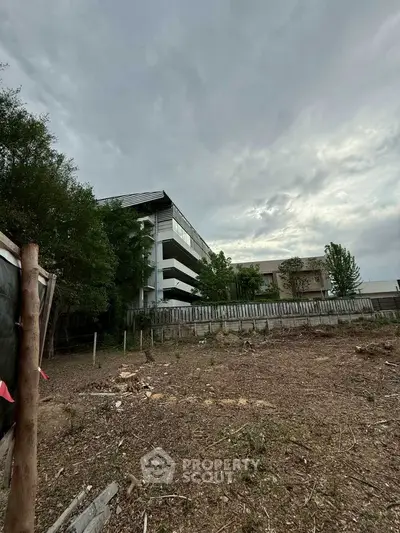Spacious land plot with potential for development near modern residential building.