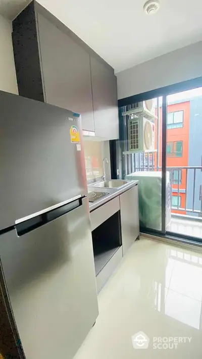 Modern kitchen with stainless steel appliances and ample cabinetry, opening onto a sunny balcony with urban views.