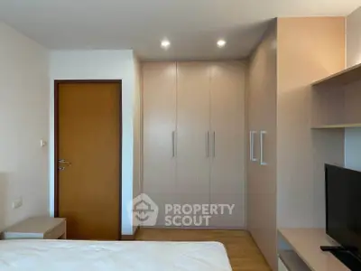 Modern bedroom with built-in wardrobe and sleek wooden door