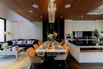 Luxurious dining room with elegant chandelier and modern kitchen in open layout design.