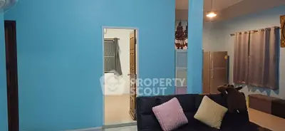 Cozy living room with blue walls, black sofa, and modern kitchen appliances.