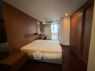 Spacious bedroom with wooden accents and balcony access in modern apartment.