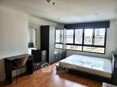 Spacious bedroom with city view, modern furniture, and ample natural light.