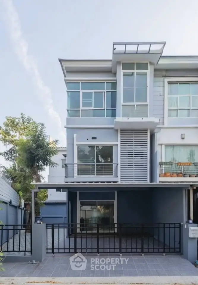Modern three-story townhouse with large windows and sleek design in a suburban neighborhood.