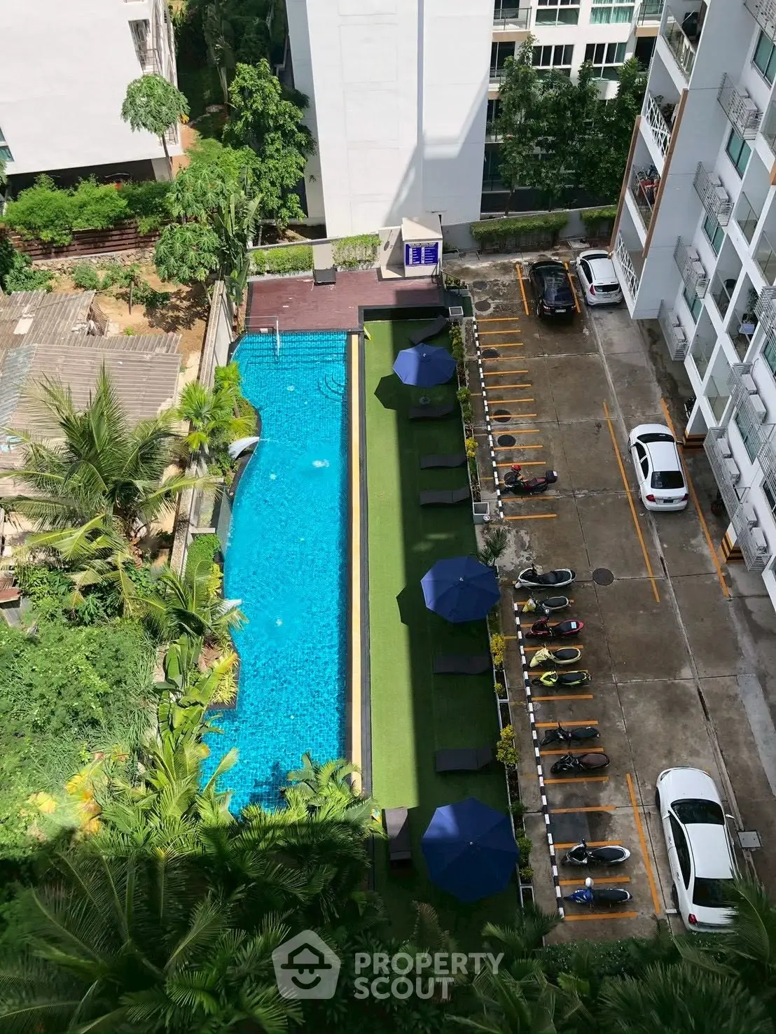Stunning aerial view of modern apartment complex with inviting pool and lush greenery, perfect for urban living.