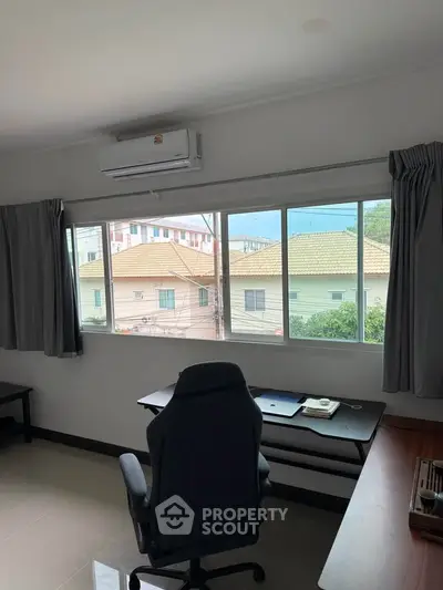 Bright study room with large window and modern desk overlooking suburban homes.